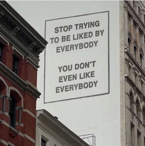 Pretend billboard on the side of a building that says, "Stop trying to be liked by everybody. You don't even like everybody."