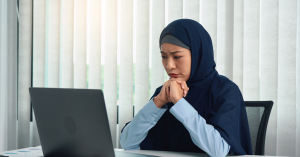 Muslim woman upset while looking at computer screen